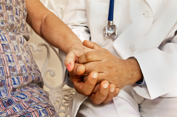 Doctor holding a senior patients hand outside in the courtyard of the nursing home